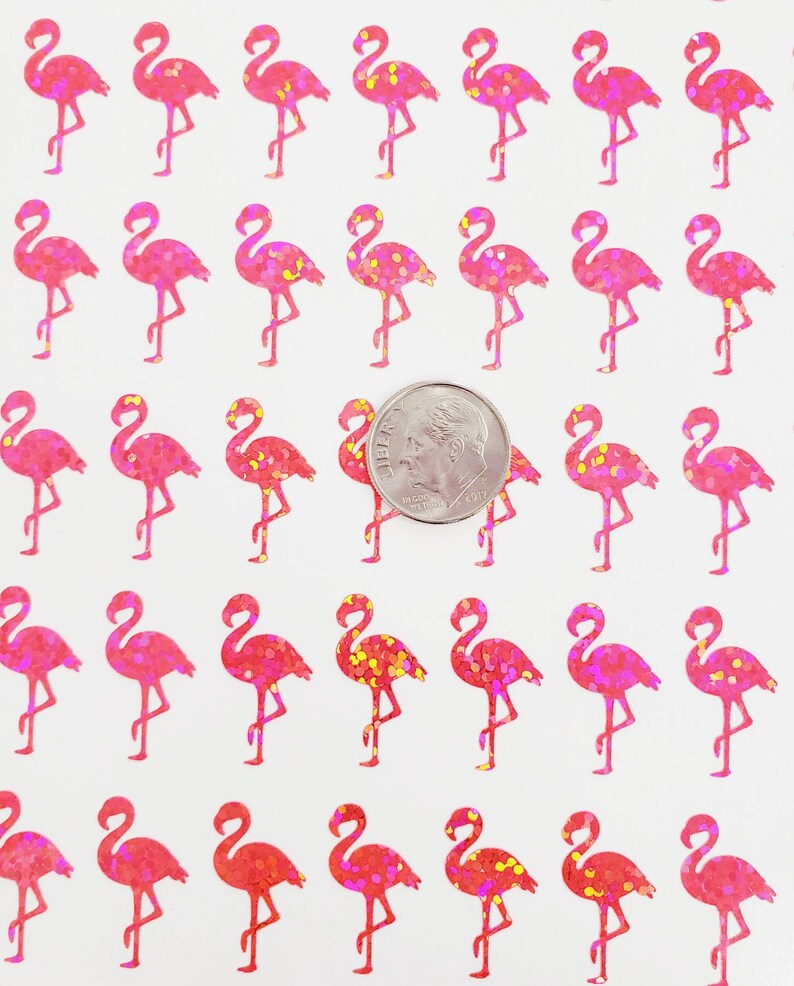 May include: Sheet of pink glitter flamingo stickers. Each flamingo is standing on one leg with its neck curved. A dime is included for size reference. The stickers have a glittery texture and are on a white background.