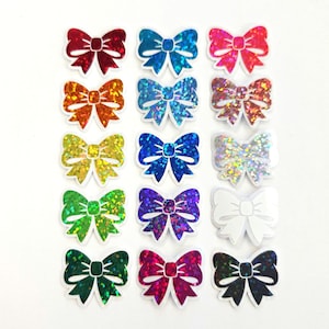 May include: A collection of colorful bow stickers in various shades, including red, blue, pink, orange, yellow, green, purple, and white. Each bow has a glittery, iridescent finish, perfect for crafts and decorations.
