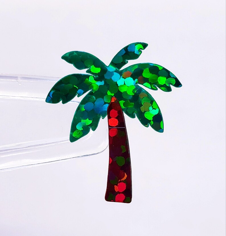 Op de afbeelding: Een groene en rode glitter palmboom uitsnede. De palmboom heeft een groene stam en groene bladeren. De bladeren zijn gemaakt van glitter en hebben een holografisch effect.