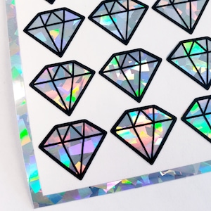 May include: A sheet of iridescent diamond stickers with a black outline. The stickers are arranged in a grid pattern on a white background.
