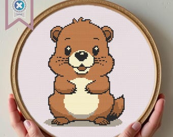 Può includere: Schema di punto croce di una marmotta di cartone animato marrone con pancia bianca e coda marrone chiaro. La marmotta è in piedi su uno sfondo bianco.