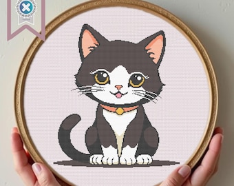 May include: A black and white cat with a white patch on its chest and a yellow collar. The cat is sitting with its paws tucked under its body and has a happy expression on its face.