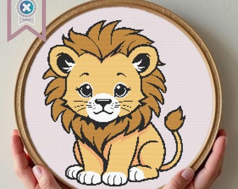 May include: A cute cartoon lion cub with a brown mane and a light brown body. The lion cub is sitting with its paws tucked under its body and has a friendly expression on its face.
