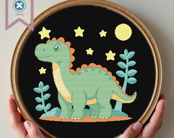 May include: A cross-stitch pattern featuring a green dinosaur with a yellow belly, standing on a brown ground with green plants. The dinosaur is surrounded by yellow stars on a black background.