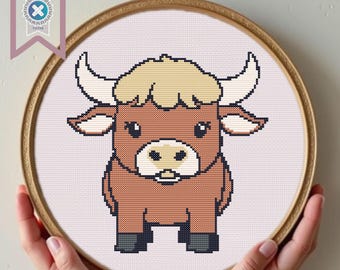 May include: A brown and white cartoon bull with a light pink background. The bull has a light brown nose, black eyes, and a light brown mouth. The bull is standing on a white surface.
