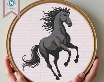 May include: A black horse with a flowing mane and tail, standing on its hind legs with its front legs raised. The horse is depicted in a cross-stitch style.