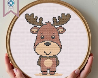 May include: A brown and beige cartoon moose cross stitch pattern in a round embroidery hoop.