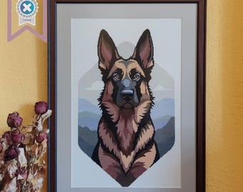 May include: Framed cross-stitch portrait of a German Shepherd dog. The dog is depicted with brown, black, and tan fur, with a detailed face and alert expression. The background features a mountain landscape in shades of blue and gray.