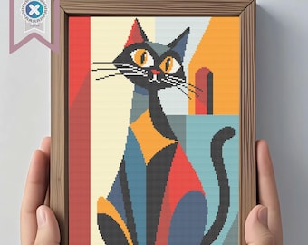 May include: A framed cross-stitch art piece featuring a stylized black cat with orange eyes and geometric shapes in red, blue, and orange. The artwork is in a wooden frame and includes a PDF download logo.