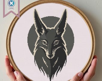 May include: A cross-stitch pattern of a fox's head in shades of gray, set against a gray circle, within a wooden embroidery hoop. The fox has pointed ears and a detailed face. A banner in the upper left corner reads "PDF Download".