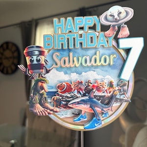Może przedstawiać: Kolorowa dekoracja na tort urodzinowy z napisem "HAPPY BIRTHDAY Salvador" i cyfrą "7". Projekt zawiera postacie z kresk&oacute;wek, rekina w niebieskich trampkach i filiżankę kawy.