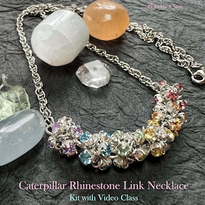 May include: A silver chain necklace with a colorful rhinestone caterpillar design. The necklace features a variety of colored rhinestones, including pink, blue, green, and yellow. The image also includes various gemstones and the text "Caterpillar Rhinestone Link Necklace Kit with Video Class."