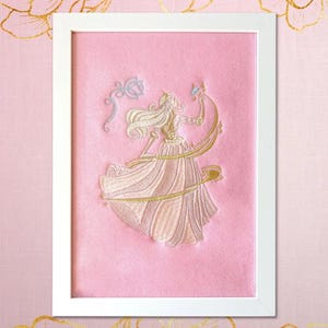 Pink embroidery detail of the princess in a gold-pink dress surrounded by magical gold particles.