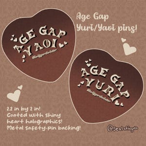 May include: Two heart-shaped pins with the text "Age Gap Yuri/Yaoi" in white, with the phrase "The bigger the better" below. The pins are 2.2 inches by 2 inches, coated with shiny heart holographics and have metal safety-pin backings.