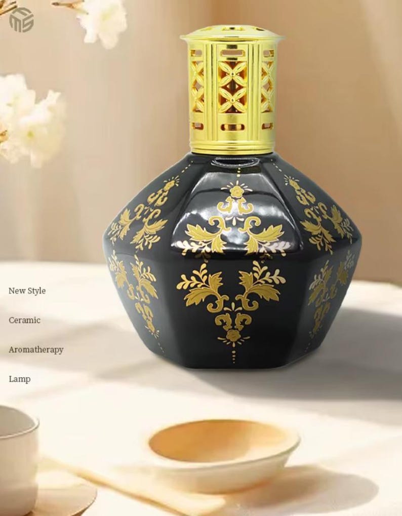 May include: A black ceramic aromatherapy lamp with gold floral designs. The lamp has a gold-colored top and is labeled "New Style", "Ceramic", "Aromatherapy", and "Lamp". The lamp is an elegant home decor item.