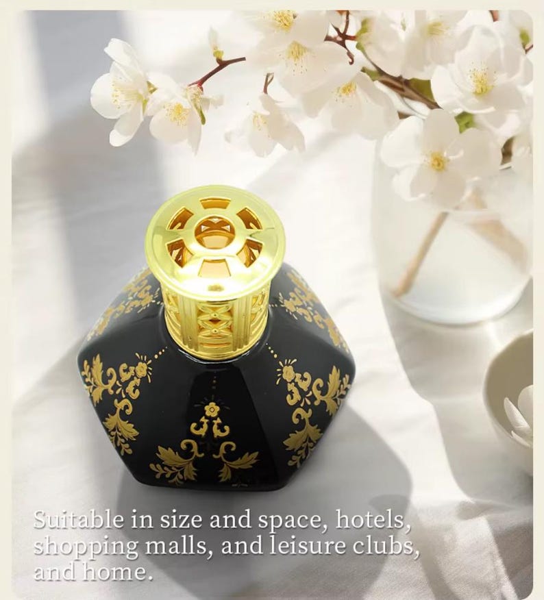 May include: Black hexagonal fragrance diffuser with gold filigree design and a gold top. The diffuser is decorated with gold floral patterns. White flowers in a glass vase are in the background. The text on the image says: Suitable in size and space, hotels, shopping malls, and leisure clubs, and home.