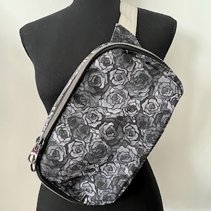 May include: A black fanny pack with a white strap and a black and white rose print.