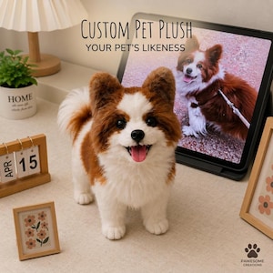 Può includere: Un peluche di cane personalizzato con pelo marrone e bianco, in piedi con la bocca aperta e la lingua di fuori. Dietro, un tablet mostra la fotografia di un cane simile. Il testo sullo schermo recita Custom Pet Plush Your Pet's Likeness.