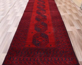 May include: A red runner rug with a traditional Persian design. The rug has a dark blue border and intricate patterns in the center.