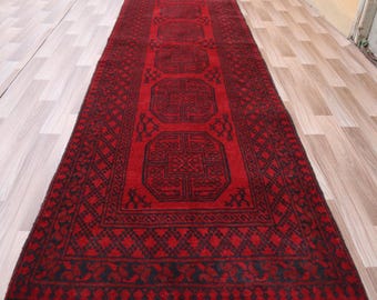 May include: A red runner rug with a black geometric pattern. The rug has a fringe border.