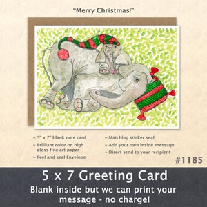 May include: A 5x7 inch greeting card featuring a watercolor illustration of two elephants wearing red and green Christmas hats. The card is blank inside and has a matching sticker seal. The text "Merry Christmas!" is at the top of the card.