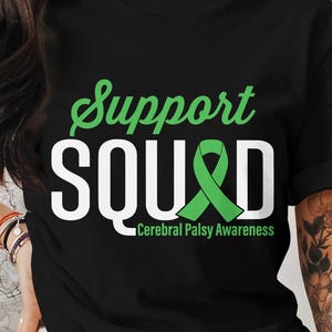May include: Black t-shirt with white text that reads "Support Squad" and a green ribbon with the text "Cerebral Palsy Awareness" underneath.