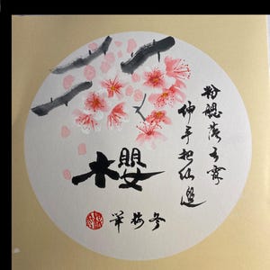 Könnte beinhalten: Ein weißer Kreis mit schwarzem Rand, der eine Malerei von rosa Kirschblüten mit schwarzen Ästen zeigt. Der Text "大安" ist in schwarzer Tinte in der Mitte des Kreises geschrieben. Der Text "春風得意" ist in schwarzer Tinte auf der rechten Seite des Kreises geschrieben. Ein roter Stempel mit dem Text "幸福" befindet sich am unteren Rand des Kreises.