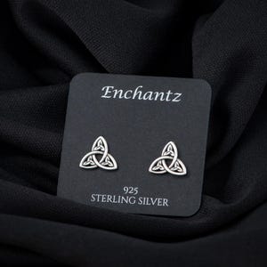 May include: A pair of silver Celtic knot earrings on a black card with the text "Enchantz 925 Sterling Silver".