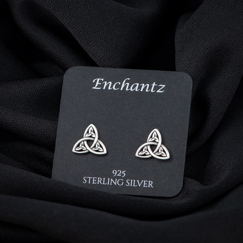 May include: A pair of silver Celtic knot earrings on a black card with the text "Enchantz 925 Sterling Silver".