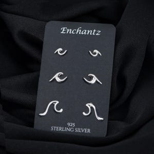 May include: A set of six silver wave earrings on a black card with the text "Enchantz 925 Sterling Silver".