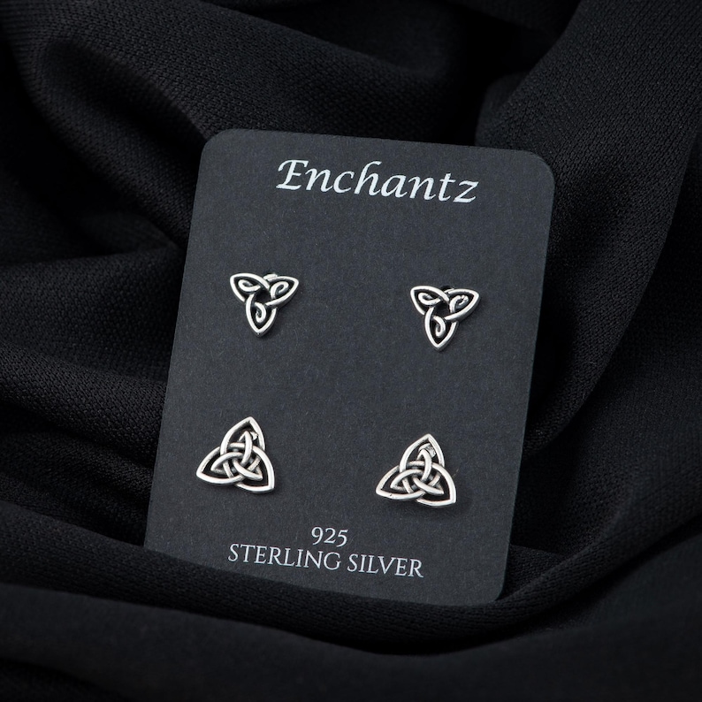 May include: A set of four silver Celtic knot earrings on a black card with the text "Enchantz 925 Sterling Silver".