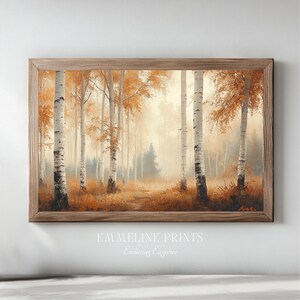 Può includere: Una stampa incorniciata di una scena di foresta con alti alberi di betulla e fogliame dorato. L'opera d'arte ha una calda tavolozza di colori autunnali, con un sentiero che conduce allo sfondo nebbioso. La cornice è in legno. Il testo "EMMELINE PRINTS" e "Enduring Elegance" è in basso.