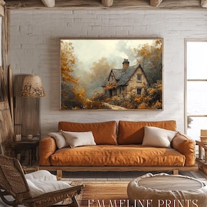 May include: A cozy living room scene featuring a framed landscape painting above a brown leather sofa with white pillows. A wooden chair, a round coffee table, and a patterned rug complete the warm, inviting space. The text "EMMELINE PRINTS Enduring Elegance" is visible.