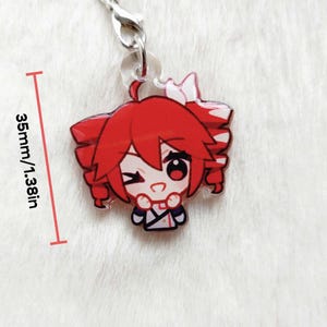 May include: A red anime-style charm with a winking character. The charm is 1.38 inches (35mm) in height and features a silver clasp. The character has red hair and is wearing a white and blue outfit.
