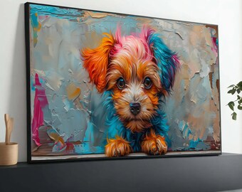 Op de afbeelding: Een ingelijste canvas print van een kleurrijke puppy. De puppy heeft oranje, roze en blauwe vacht, met grote bruine ogen. De achtergrond is een textuurmix van blauwe, grijze en roze penseelstreken. Het kunstwerk wordt op een zwart oppervlak weergegeven.