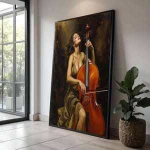 Op de afbeelding: Een ingelijste kunstdruk van een vrouw die cello speelt. De vrouw draagt een gouden jurk en staat voor de cello. De cello heeft een warme bruine kleur. De achtergrond is donker met een vleugje goud.