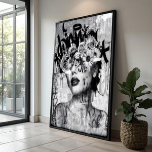 Peut inclure: Impression artistique encadrée en noir et blanc représentant un portrait de femme orné d'une couronne florale et d'éléments de style graffiti. L'œuvre présente une palette de gris avec des effets de peinture dégoulinante et des lettrages noirs audacieux.