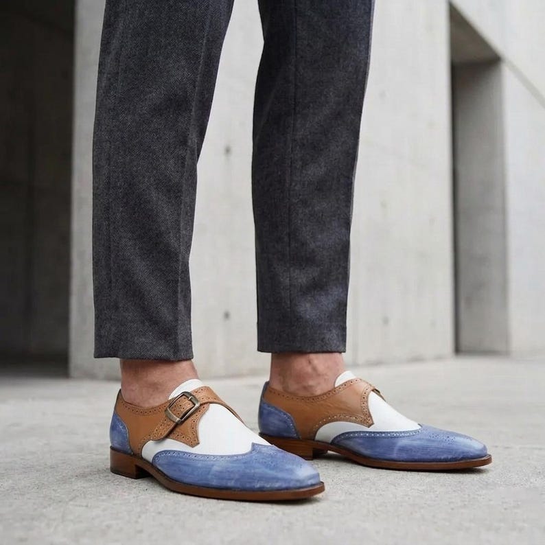 Handmade blue and white spectator monk strap shoes for men featuring premium leather construction, elegant brogue detailing, and artisan craftsmanship.

Two tone monk strap dress shoes crafted from genuine cowhide leather with vintage-inspired formal styling and durable leather sole.

Elegant handmade men’s formal shoes featuring blue leather finish, white contrast panels, monk buckle closure, and handcrafted detailing.