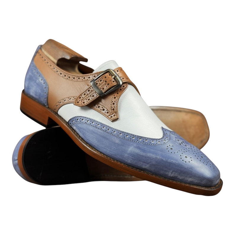 Handmade blue and white spectator monk strap shoes for men featuring premium leather construction, elegant brogue detailing, and artisan craftsmanship.

Two tone monk strap dress shoes crafted from genuine cowhide leather with vintage-inspired formal styling and durable leather sole.

Elegant handmade men’s formal shoes featuring blue leather finish, white contrast panels, monk buckle closure, and handcrafted detailing.