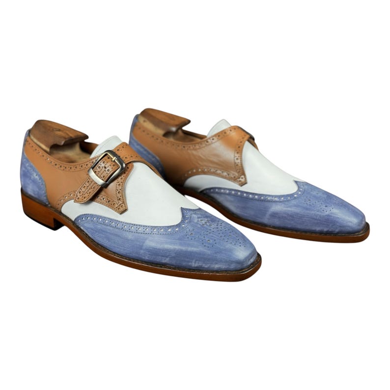 Handmade blue and white spectator monk strap shoes for men featuring premium leather construction, elegant brogue detailing, and artisan craftsmanship.

Two tone monk strap dress shoes crafted from genuine cowhide leather with vintage-inspired formal styling and durable leather sole.

Elegant handmade men’s formal shoes featuring blue leather finish, white contrast panels, monk buckle closure, and handcrafted detailing.