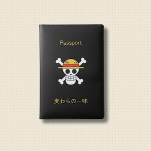 Könnte beinhalten: Schwarze Reisepasshülle mit dem Wort "Passport" in goldfarbenen Buchstaben. Verfügt über ein weißes Totenkopf- und gekreuzte Knochen-Logo mit einem gelb-roten Hut. Japanischer Text darunter.