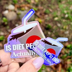 May include: Two holographic stickers shaped like a soda cup with a straw, featuring a red and blue circular logo and the white text IS DIET PEPSI OK? Actually, no. The stickers have a reflective, iridescent finish that shifts colors in the light.