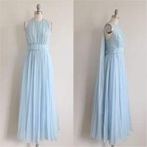 May include: A light blue, floor-length gown with a halter neckline and a cinched waist. The dress features a flowing, pleated skirt and a matching sash. The dress is displayed on a mannequin.