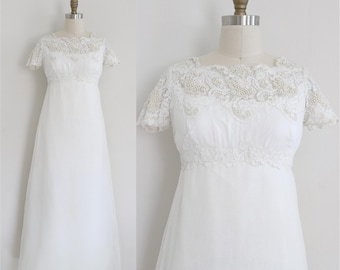 May include: A white vintage wedding dress with a lace bodice and a flowing skirt.
