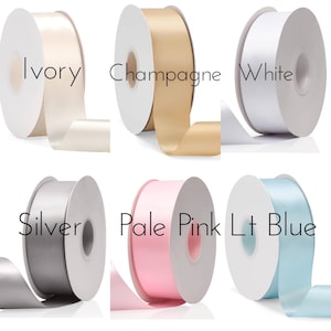 May include: Six spools of ribbon in various colors, including ivory, champagne, white, silver, pale pink, and light blue. The ribbon is wrapped around the spools and the colors are clearly visible.