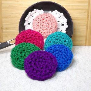 以下が含まれることがあります： ピンク、グリーン、ブルー、パープルなど、さまざまな色のクロシェ編みスクラバーが6つ、木製の表面に並べられています。スクラバーは円形で、テクスチャのあるクロシェ編みのデザインになっています。