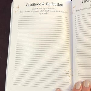 May include: Open journal with lined pages. The title "Gratitude & Reflection" is at the top, with text below that reads "Gratitude is the key to abundance. Take a moment to appreciate what's already in your life, no matter how big or small."