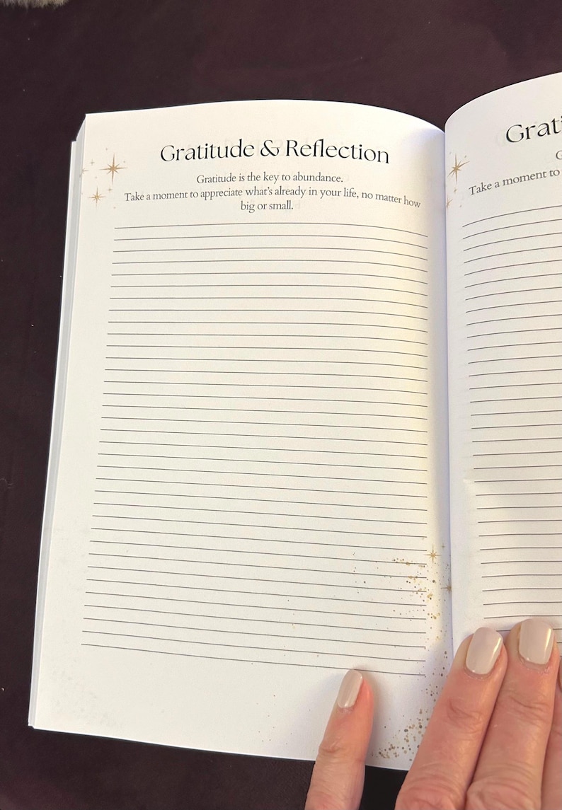 May include: Open journal with lined pages. The title "Gratitude & Reflection" is at the top, with text below that reads "Gratitude is the key to abundance. Take a moment to appreciate what's already in your life, no matter how big or small."