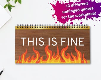 May include: A spiral-bound notepad with a wooden-look cover. The notepad features the phrase "THIS IS FINE" above a graphic of flames. The image also includes a laptop, coffee cup, pens, and a notepad on a white surface.