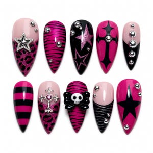 May include: A set of ten almond-shaped press-on nails featuring a pink and black color palette. Designs include leopard print, zebra stripes, horizontal stripes, stars, crosses, a skull with a bow, and silver metallic spheres as accents.